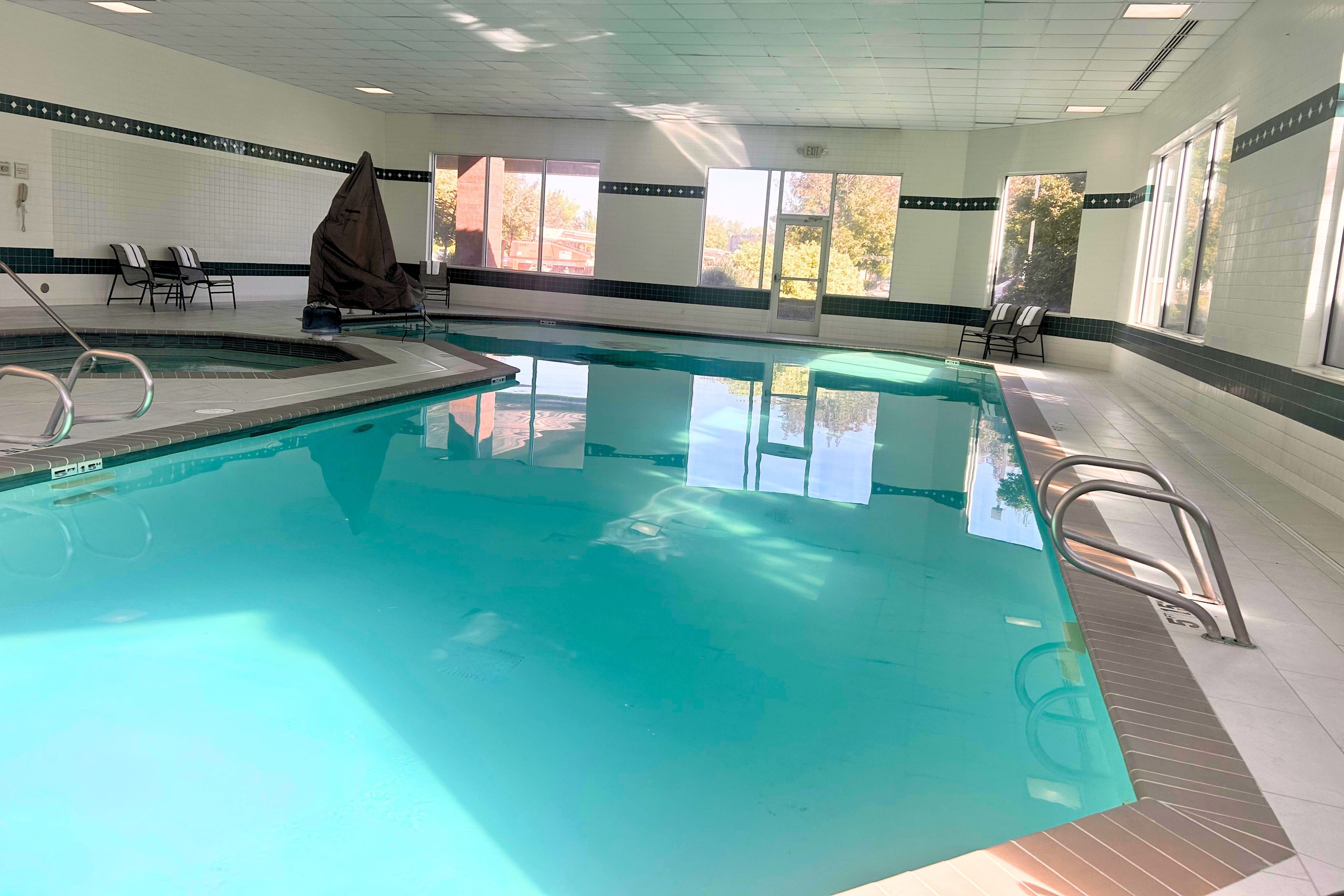 Une piscine intérieure à l’eau claire, entourée de chaises longues et d’un espace de repos abrité.