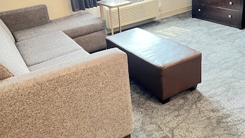 A living room with a sectional sofa, a coffee table, a TV, and a dresser.