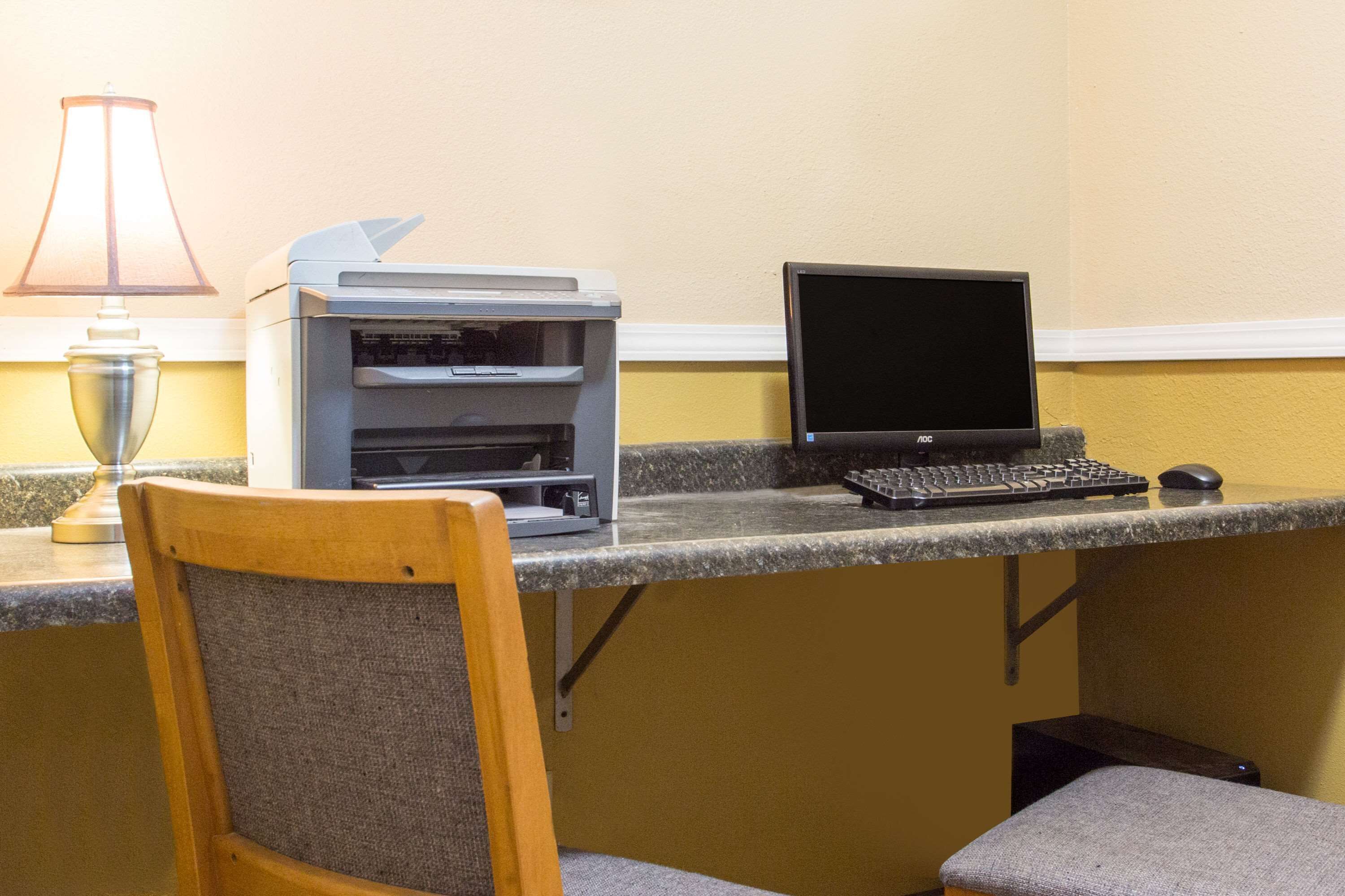 A workspace with a desktop computer, a printer, and a lamp.