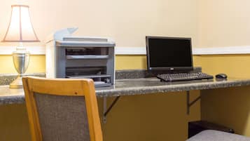 A workspace with a desktop computer, a printer, and a lamp.