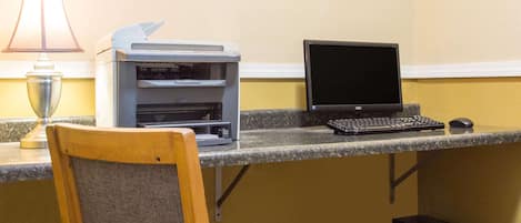 A workspace with a desktop computer, a printer, and a lamp.