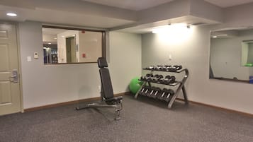 A gym with a bench, dumbbells, and exercise balls.