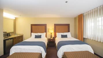 Habitación de hotel con dos camas, un escritorio, un microondas y una ventana con cortinas.