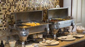A buffet setup with two open buffet stations, serving trays, and various utensils on a granite countertop.