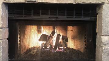 Une cheminée en pierre avec un foyer en métal et un feu qui crépite à l’intérieur.