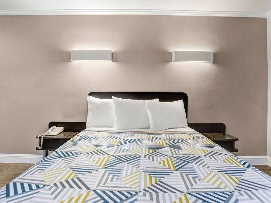 A hotel room with a bed, two bedside tables, a phone, and two wall-mounted lights.