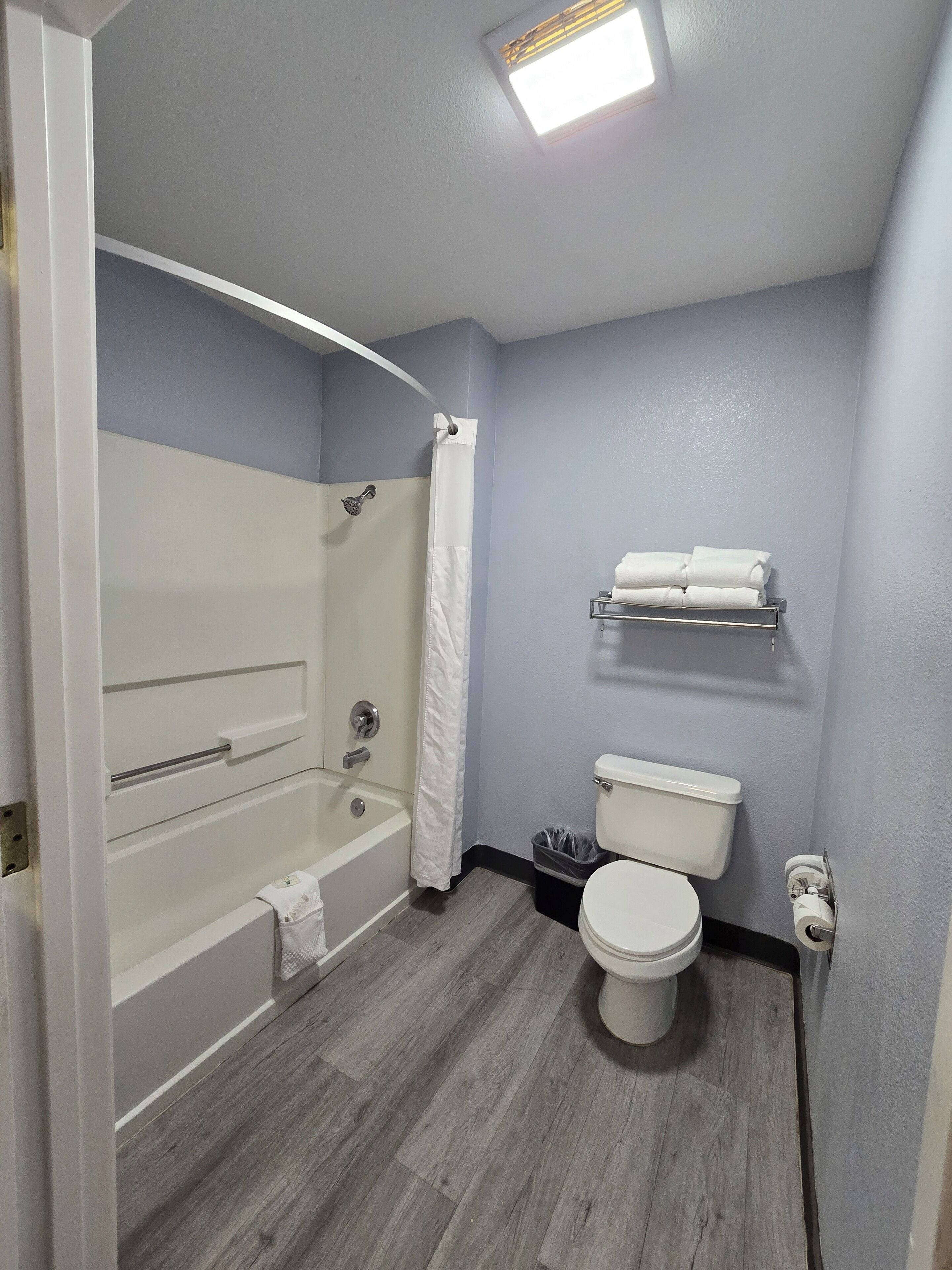 A bathroom with a bathtub, toilet, and shower curtain.