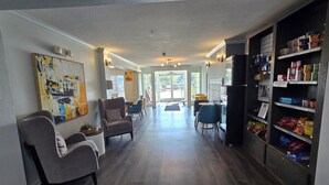 Un intérieur moderne avec un plancher en bois, un coin salon avec des fauteuils, un coin repas avec une table et des chaises, et un garde-manger bien approvisionné en produits alimentaires.