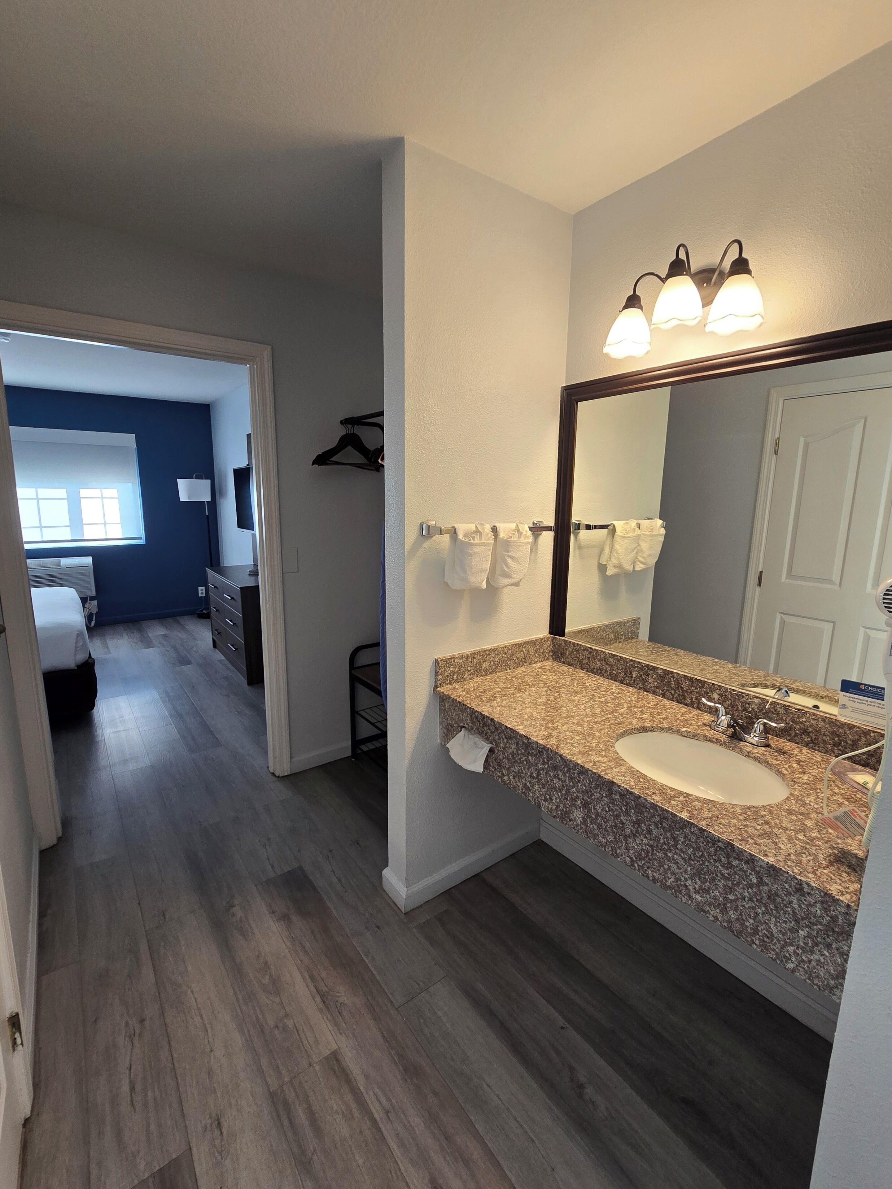 A modern bathroom with a granite countertop, a large mirror, and a vanity.