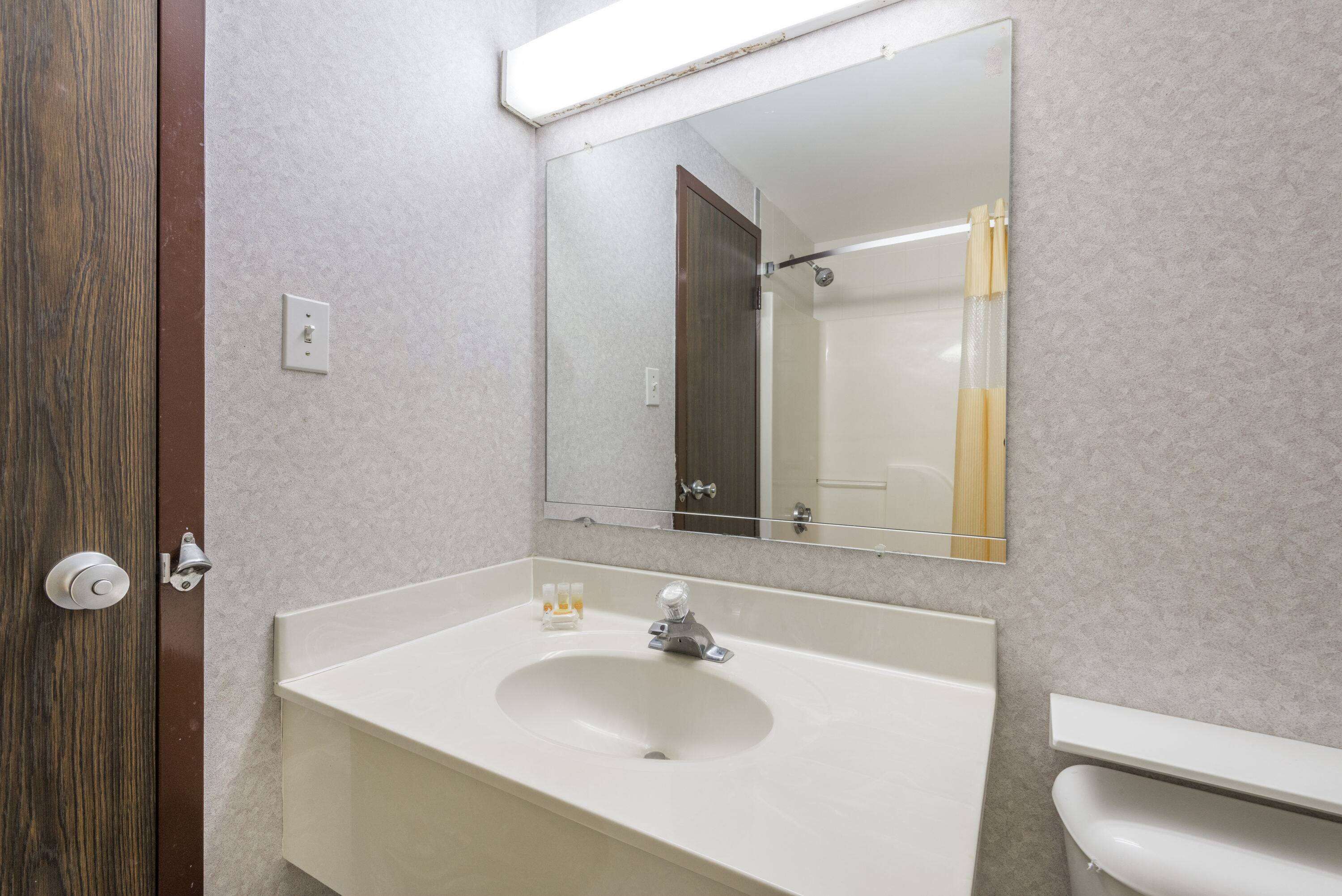 Un baño con lavamanos blanco, un espejo y un inodoro.