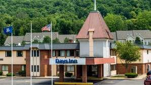 A Days Inn with a brick facade, a red roof, and a parking lot in front. - Days Inn by Wyndham Berlin Meriden (Berlin)