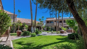 A hotel courtyard with palm trees, a fountain, and a building with a tiled roof. - La Fuente Inn & Suites (Yuma)