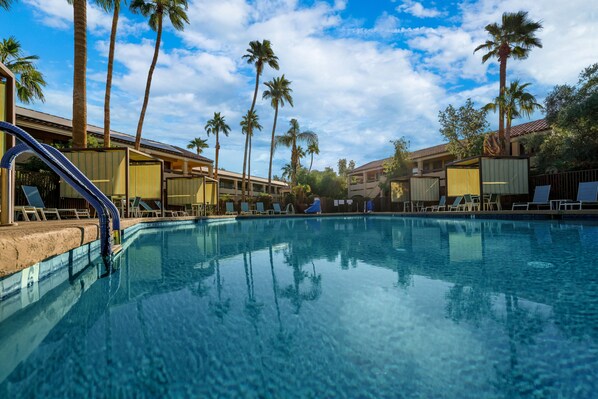 Relax by the resort pool surrounded by palm trees and lounge chairs.