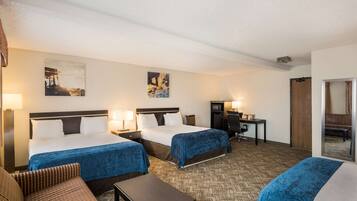 A hotel room with two beds, a desk, a chair, and a sofa.