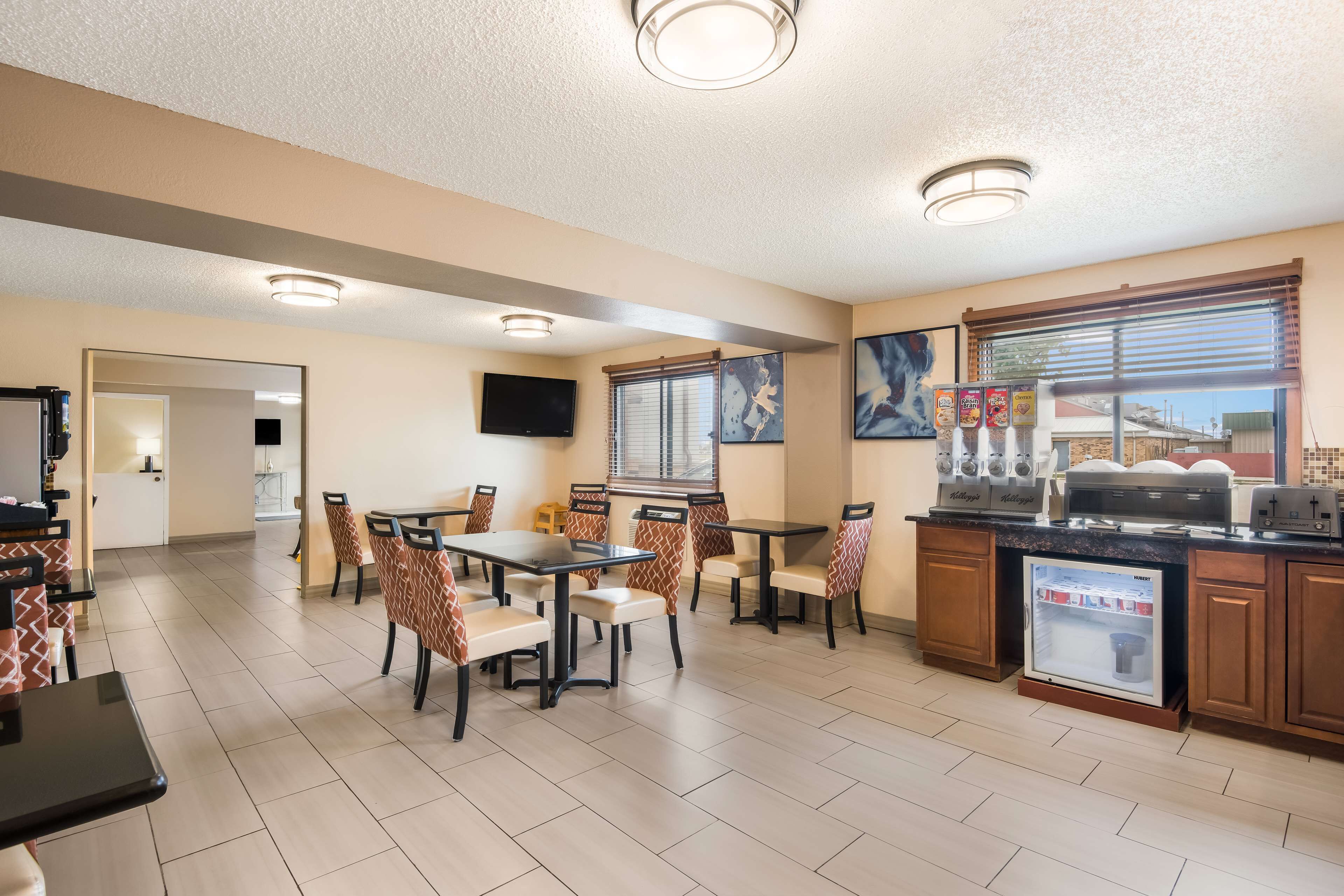 A hotel dining area with tables and chairs, a refrigerator, and a coffee station.