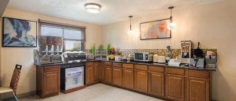 A kitchen with wooden cabinets, a refrigerator, a microwave, and a coffee maker.