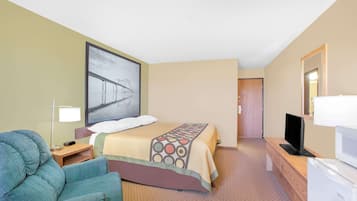 Quarto de hotel com cama, televisão, escrivaninha, cadeira e um quadro na parede.