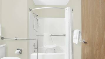 Un baño con bañera, ducha, inodoro y puerta de madera.