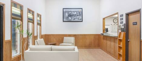 A reception area with a white sofa, a potted plant, and a framed picture on the wall.