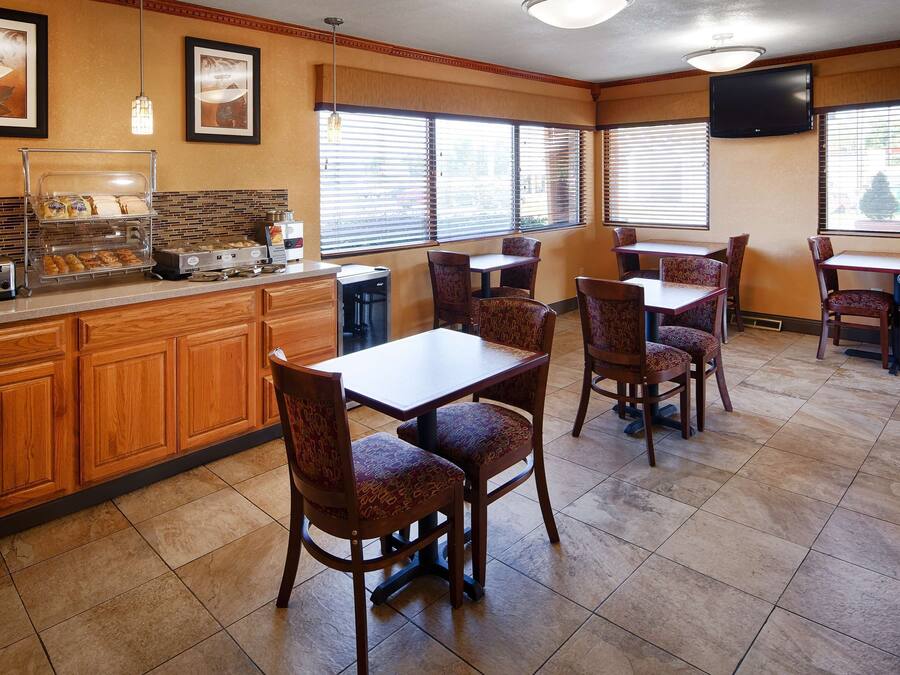 A hotel dining area with wooden cabinets, a buffet counter, and patterned chairs.