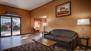 A hotel lobby with a leather sofa, a small table, a lamp, and a painting on the wall. - Best Western Martinsville Inn (Martinsville)
