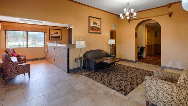 A spacious living room with a large window, a fireplace, a sofa, a coffee table, and a patterned rug. - Best Western Martinsville Inn (Martinsville)