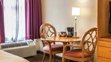 Habitación de hotel con cama, escritorio, silla, lámpara y armario.