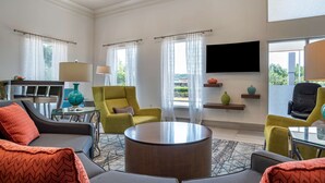 A modern living room with a sofa, armchairs, a coffee table, and a flat-screen TV mounted on the wall. - Best Western Carlton Suites (Birmingham)