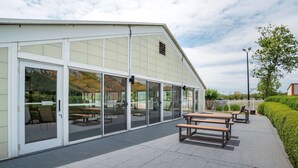 A building with large glass doors, a paved patio area with wooden benches, and a well-maintained hedge. - Best Western Carlton Suites (Birmingham)