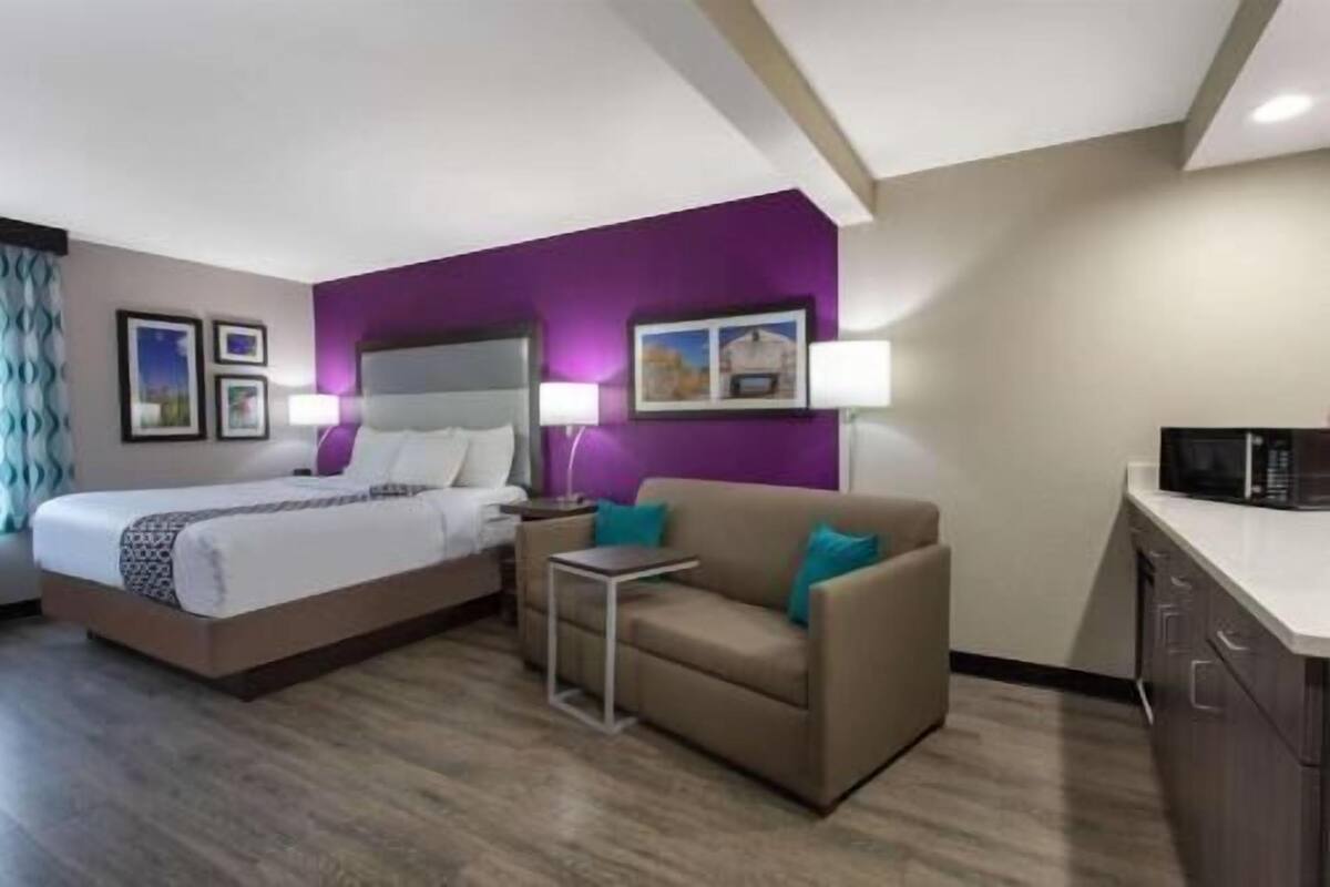 A hotel room with a bed, a sofa, a small table, and a microwave.