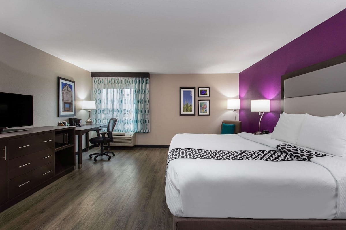 A hotel room with a bed, desk, TV, and two lamps.