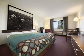 Une chambre d’hôtel avec un grand lit, un bureau, une chaise, une télévision et une fenêtre avec des rideaux.