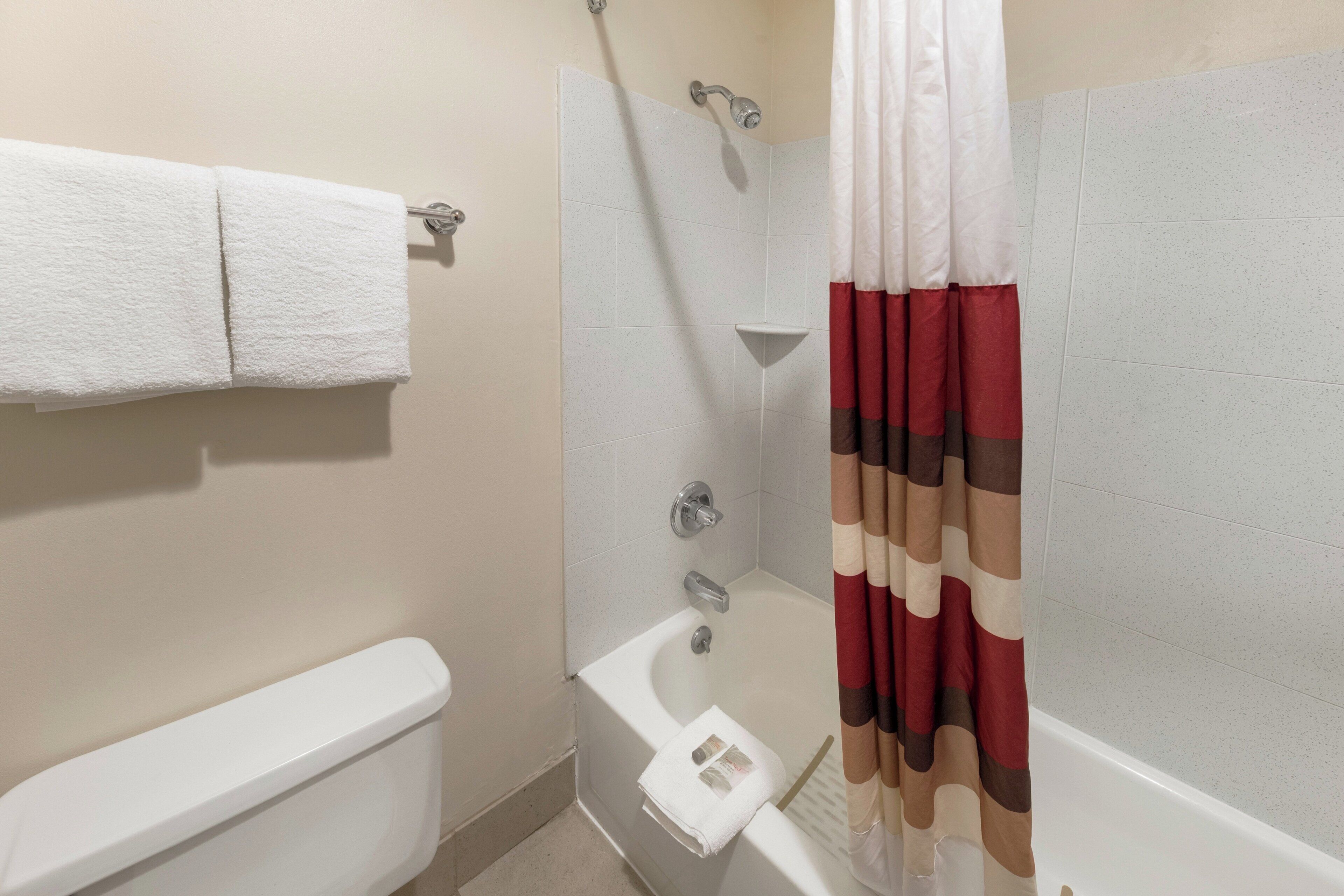 Un baño con inodoro, ducha con cortina y un perchero para toallas.
