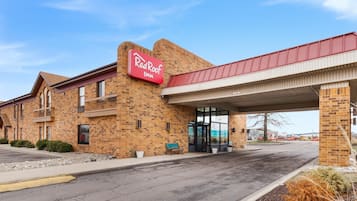 Un hôtel Red Roof Inn avec une façade en briques, une entrée abritée et un parking.