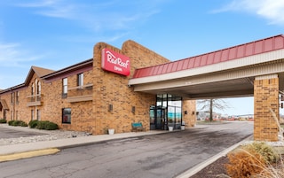 Un hotel Red Roof Inn con fachada de ladrillo, un acceso cubierto y un estacionamiento.
