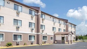 A multi-story hotel with a flat facade, air conditioning units, and a parking lot. - Boarders Inn & Suites by Cobblestone Hotels - Waterloo/Cedar Falls (Waterloo)