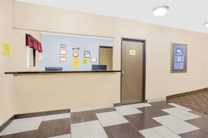 Zona de recepción con mostrador, puerta, certificados enmarcados en la pared y suelo estampado.