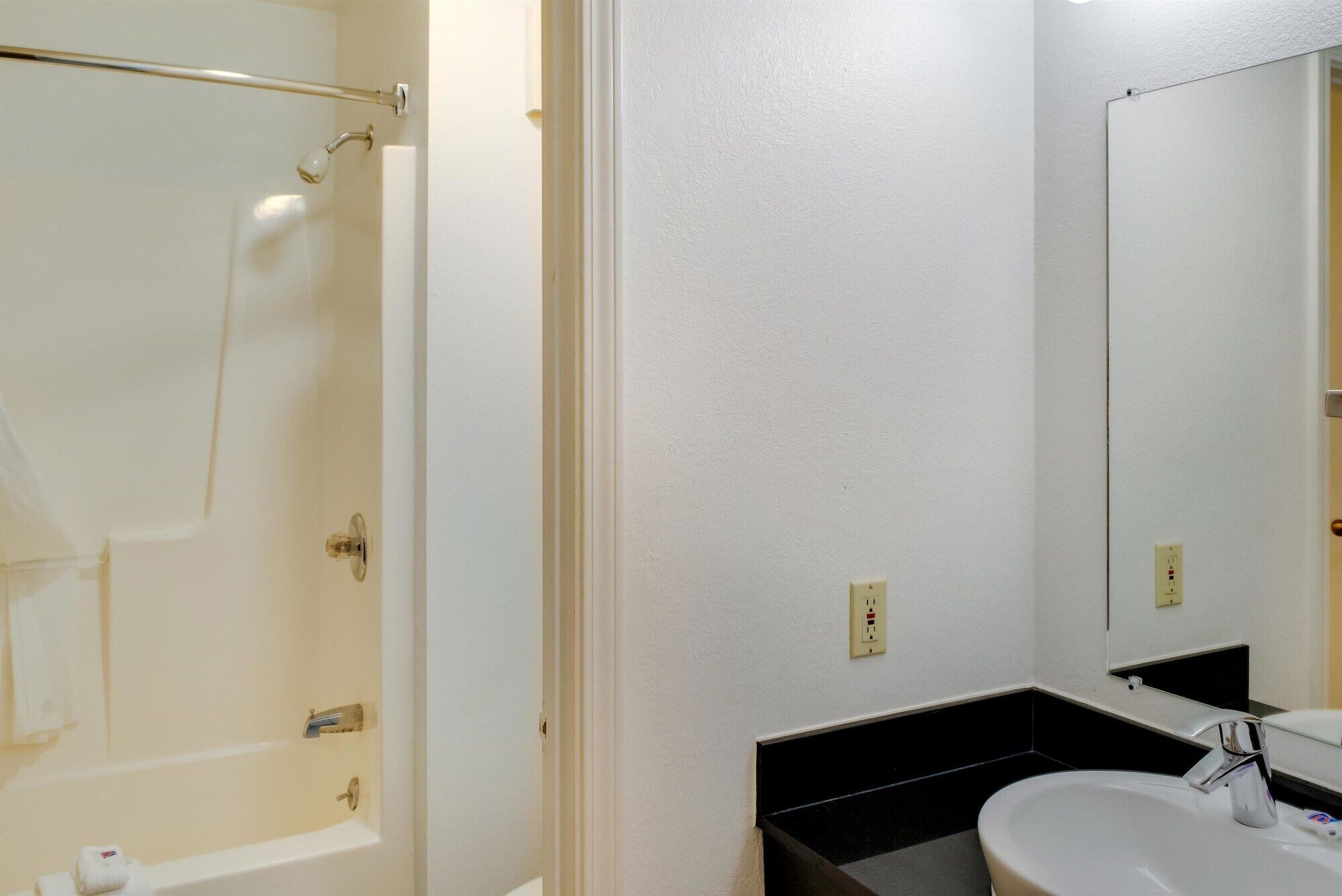 A bathroom with a bathtub, a sink, and a mirror.