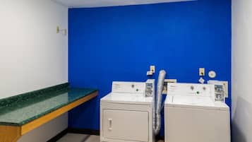 Lavandería con dos lavadoras y secadoras Whirlpool, una encimera verde y una pared azul.