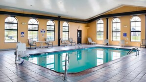 A large indoor swimming pool with multiple seating areas and a clear view of the outdoors through large windows. - Motel 6 Richmond, IN (Richmond)