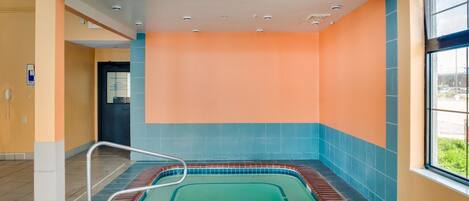 A spa area with a hot tub, tiled walls, and a window providing a view.