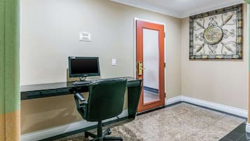 Una habitación con escritorio, silla, computadora y una puerta con un cartel encima.