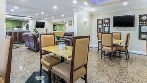 A hotel lobby with a reception desk, seating area, and a television mounted on the wall. - Quality Inn & Suites (College Park)