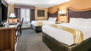 A hotel room with two beds, a desk, a TV, and a window with curtains. - Quality Inn & Suites (College Park)