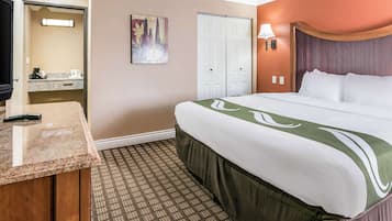 Una habitación de hotel con cama, escritorio, baño y un cuadro en la pared.