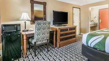 Habitación de hotel con cama, escritorio con televisor, microondas, teléfono y cómoda.