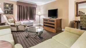 A living room with a sofa, armchair, and a glass coffee table. - Quality Inn & Suites (College Park)