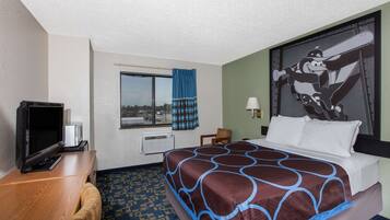Habitación de hotel con cama, escritorio con televisor, ventana con cortinas y lámpara de pared.