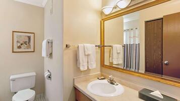 A bathroom with a toilet, sink, mirror, and towels.