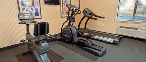 Un gimnasio con cinta de correr, elíptica y bicicleta estática.